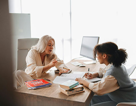 Two women sat at a table with paperwork